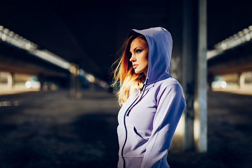 Portrait of a young beautiful woman in a hoodie in an urban environment