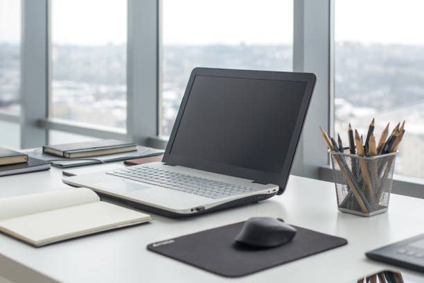 istock Sideview of office desktop with blank laptop and various tools. 648525280