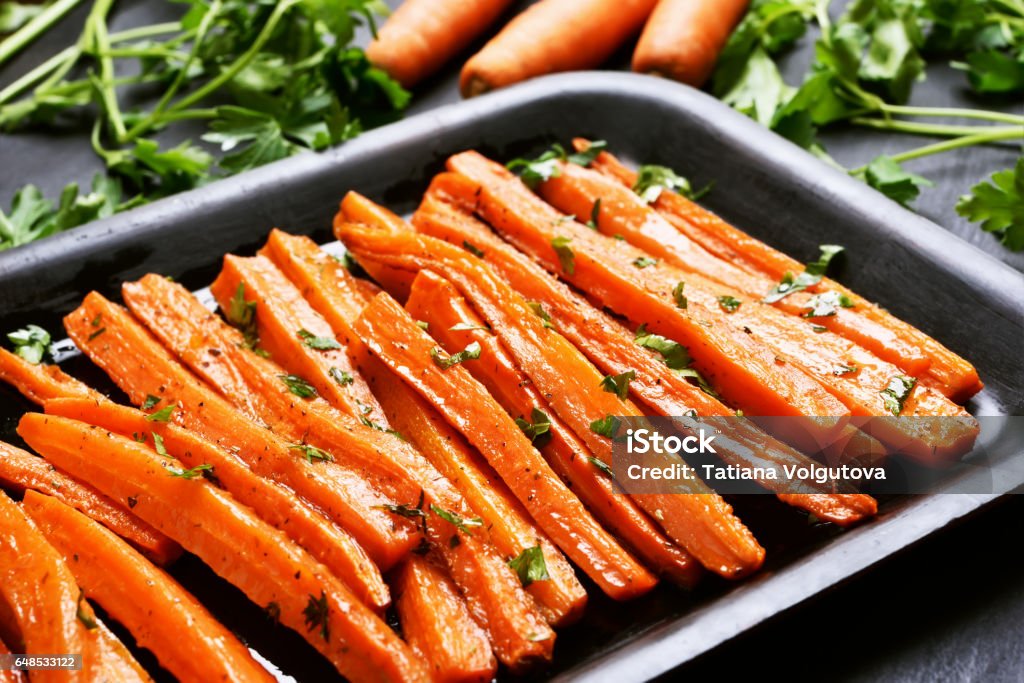 Roasted carrots Fried carrots with green herbs in baking tray, close up Carrot Stock Photo