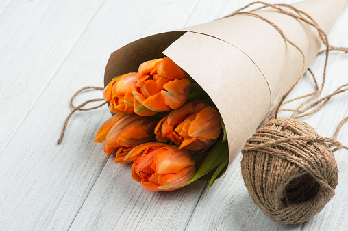 Spring greeting card with orange tulips in kraft paper, twine. Space for text. country cottage rustic style. valentine's day, romantic, love concept