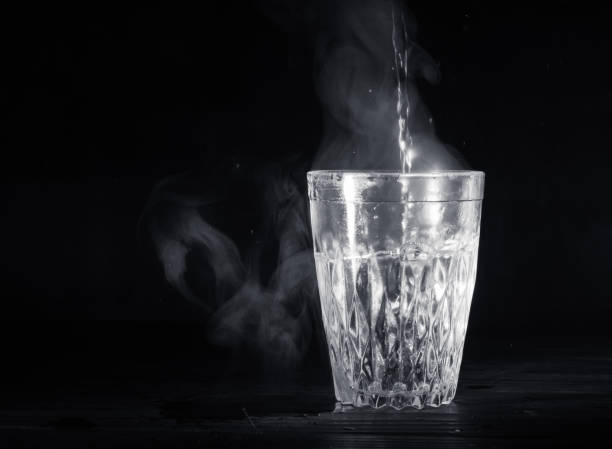 Transparent glass cup with swell the boiling water into it. Transparent glass cup with swell the boiling water into it. The vapor from the top. Black background. Space for text. glass cup of boiling water stock pictures, royalty-free photos & images