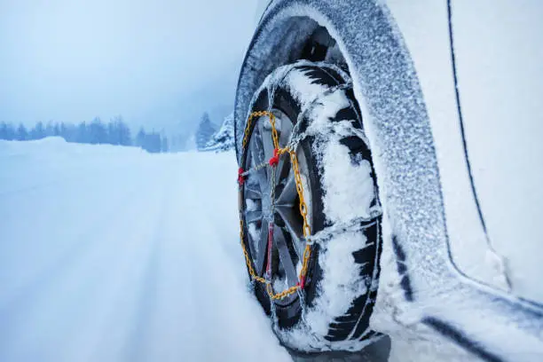 Photo of Car with snow chains for tire on snowcapped road