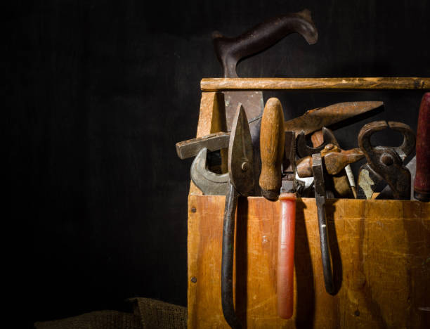 Old used tools in the toolbox. Dark background. spot lighting. Wooden box. Repair work.