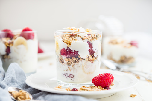Healthy Energy-boosting Breakfast made from Homemade Nut and Seeds Granola, Yogurt, Raspberries, Banana and Maple Syrup