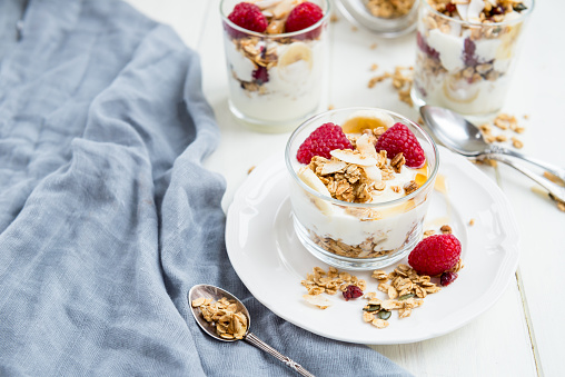 Healthy Energy-boosting Breakfast made from Homemade Nut and Seeds Granola, Yogurt, Raspberries, Banana and Maple Syrup