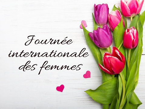 Womens day card with French words 'Journée internationale des femmes'. Tulip bouquet on white wooden background