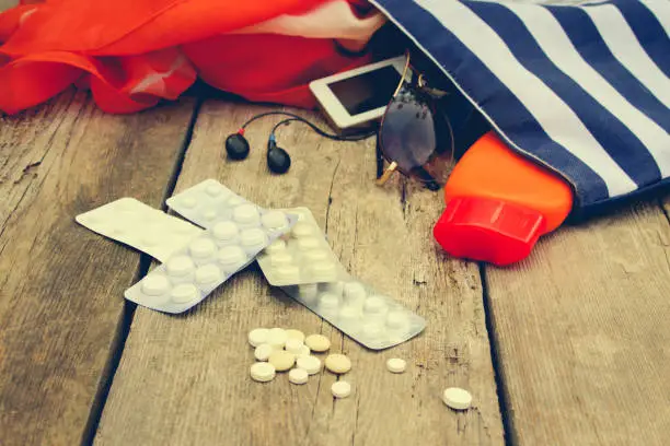 Photo of Summer women's beach accessories for your sea holiday and pill on old wooden background. Concept of medication required in journey.