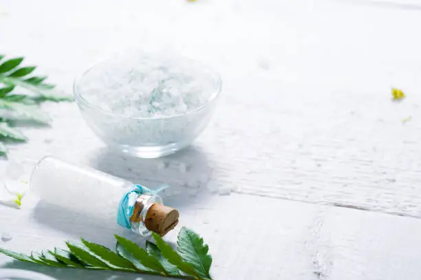 spa setting with bath salt and fern leaves on white wooden table background