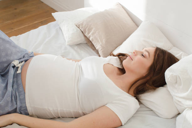istock Pregnant smiling female lying on bed 648671736