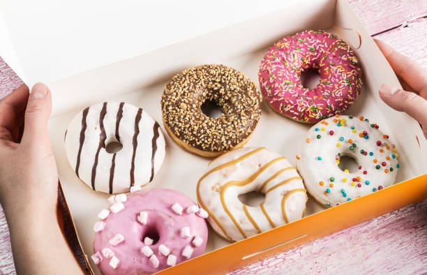 istock hands holding an open box of donuts 648675194