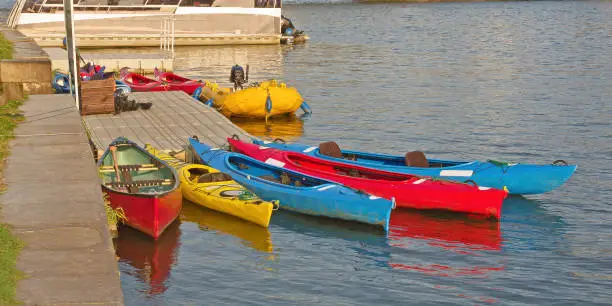 Colorful kayaks tied to the dock and waiting for adventure on the bright sunny day