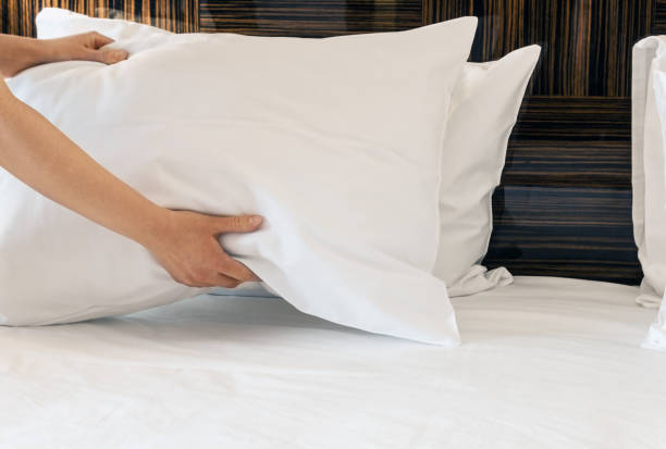 female hands corrected pillow on the bed - pillow imagens e fotografias de stock