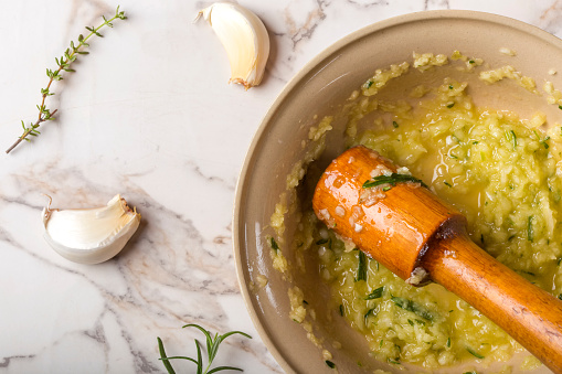 Close up of garlic sauce with lemon, thyme and rosemary in bowl on table