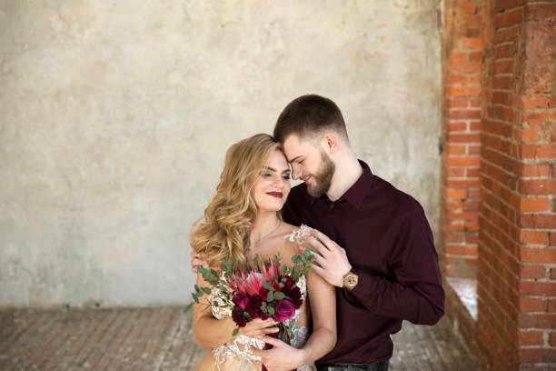 istock bride and groom posing in front of window 648694646