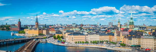 Stockholm summer spires harbour waterfront cityscape panorama Gamla Stan Sweden Blue summer skies framing the landmarks of Stockholm, Sweden's vibrant capital city, from the iconic bell tower of City Hall to the historic townhouses, restaurants and bars of Gamla Stan. kungsholmen town hall photos stock pictures, royalty-free photos & images