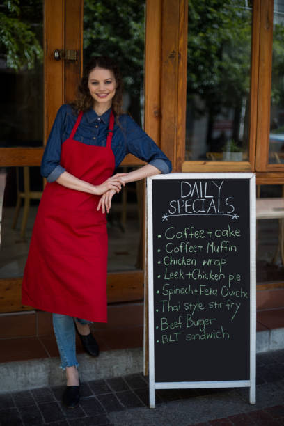 istock Smiling waitress leaning on menu board outside the cafe 648711076