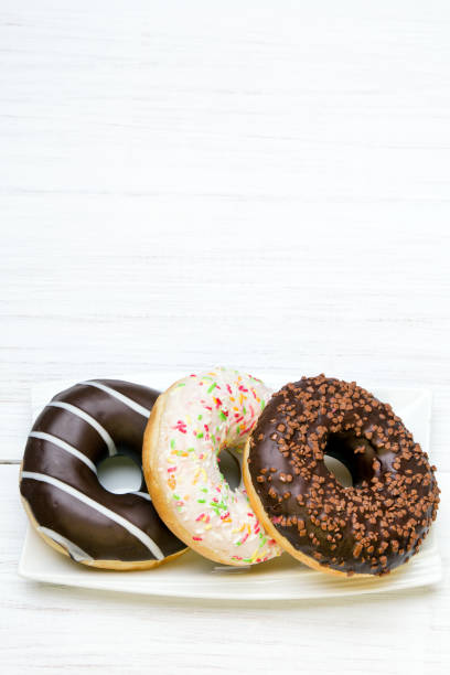 istock Tasty donuts with icing and chocolate on white wooden background 648717012