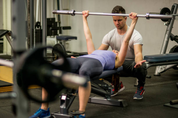 istock Personal trainer help sportswoman workout with dumbbells at the gym 648720952