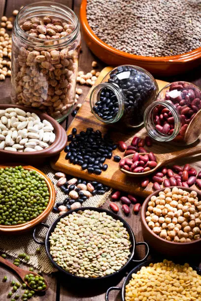 High angle view of several jars and bowls filled with dry beans shot on rustic wood table. DSRL studio photo taken with Canon EOS 5D Mk II and Canon EF 100mm f/2.8L Macro IS USM