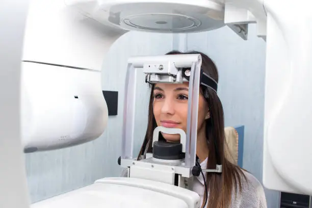 Close up head shot of girl taking dental tac with cephalometric panorama x-ray machine in clinic.