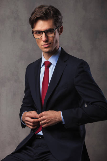 istock smiling young seated businessman buttoning his suit 648733542
