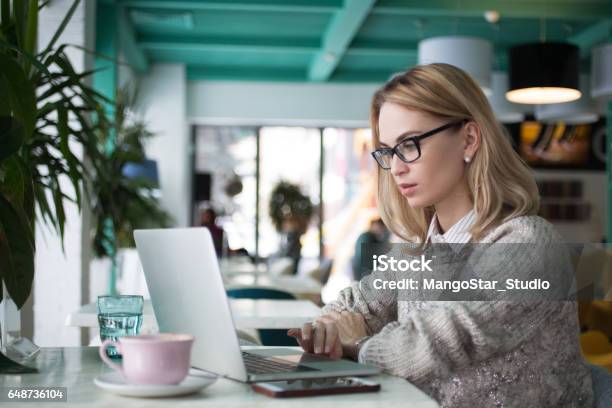 Busy Female Student Preparing For Exam In Cafe Stock Photo - Download Image Now - Article, Reading, Laptop