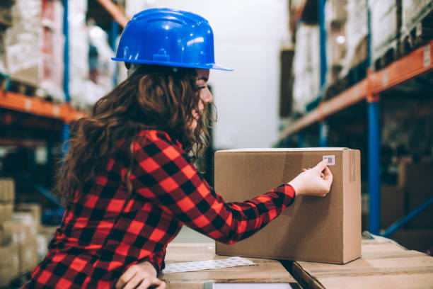 istock Young woman at a warehouse putting a bar code on a package 648741702