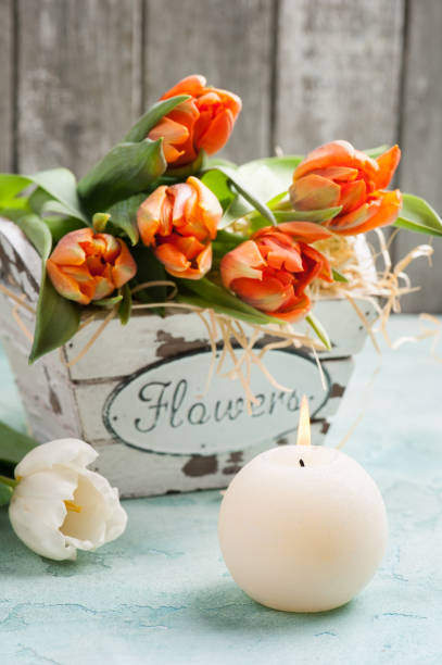 istock orange tulips in wooden basket and lit cadle 648741706