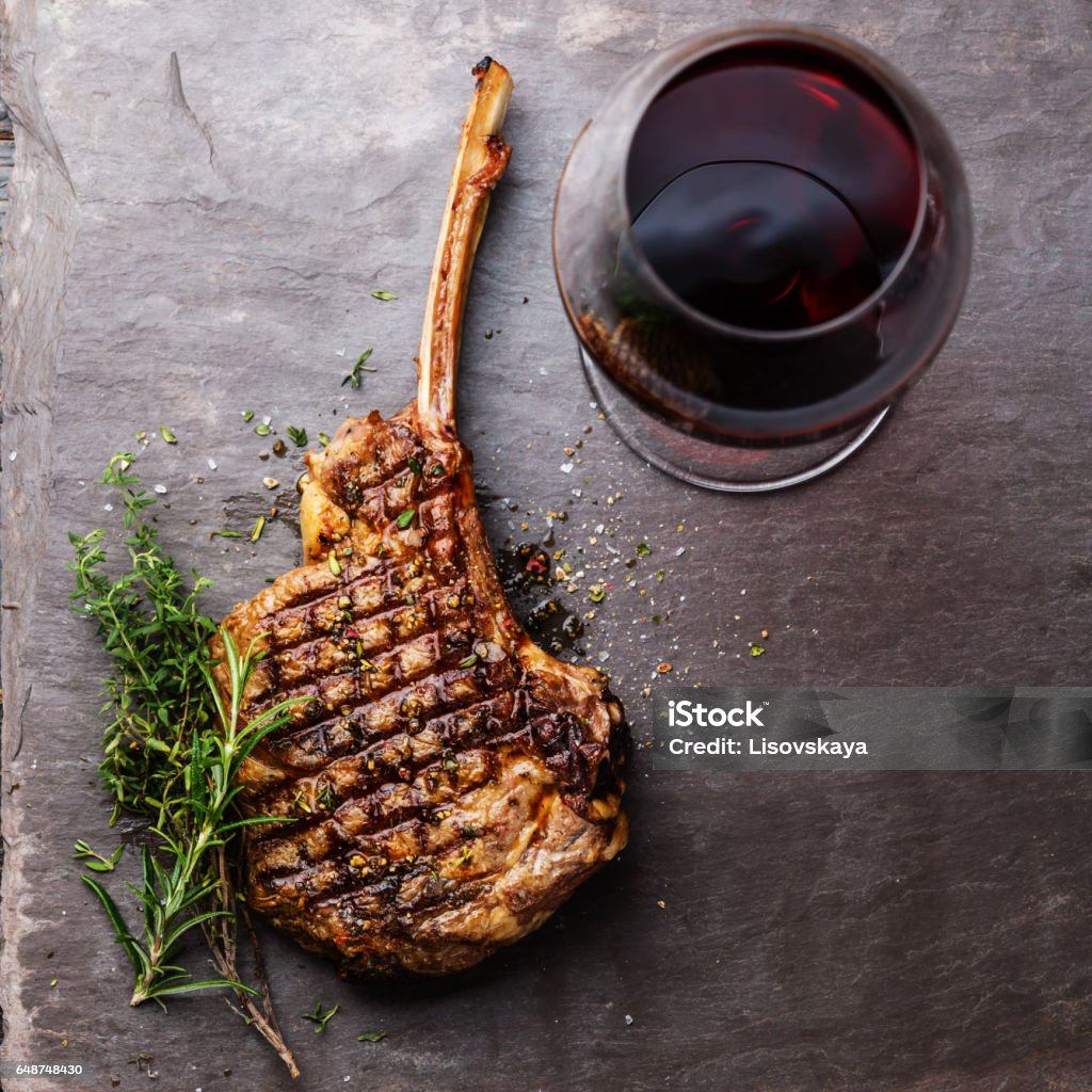 Grilled beef barbecue Veal rib Steak on bone and red wine Grilled beef barbecue Veal rib Steak on bone and red wine on stone slate background Wine Stock Photo