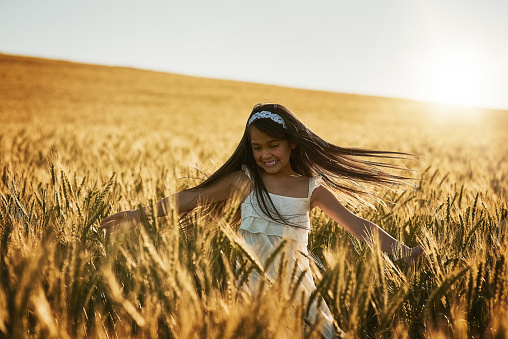 Shot of a cute little girl twirling in a cornfield