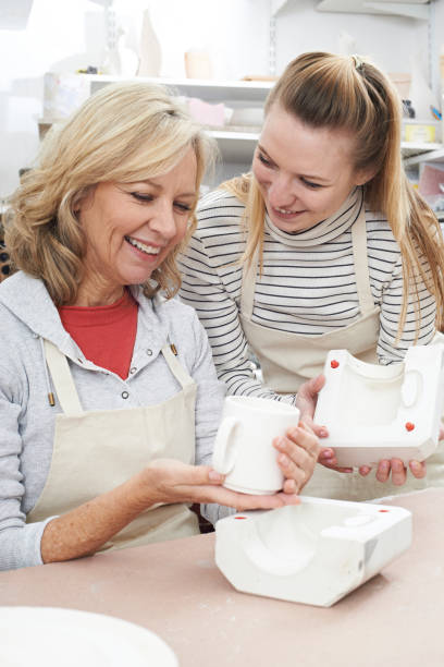 istock Teacher With Mature Woman Making Mug In Pottery Class 648759972