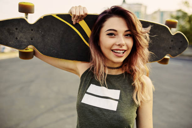 hermosa joven tatuada con longboard en tiempo soleado - teenager beautiful female men fotografías e imágenes de stock