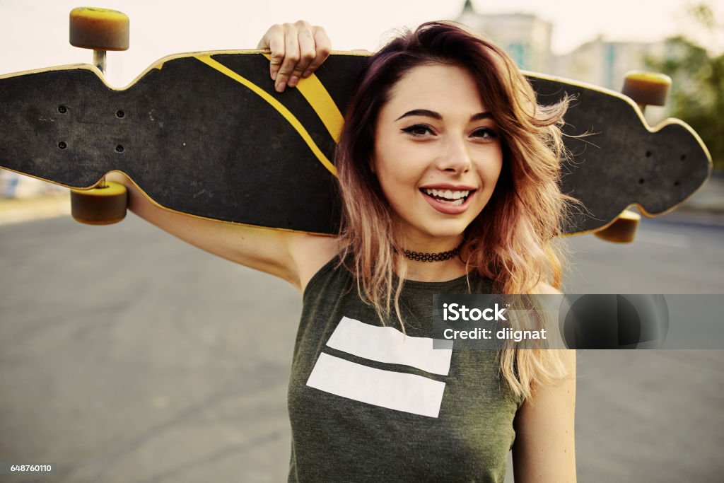 Belle jeune fille tatouée avec longboard en temps ensoleillé - Photo de Faire du skate-board libre de droits