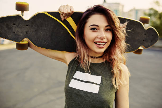 beautiful young tattooed girl with longboard in sunny weather - skate imagens e fotografias de stock