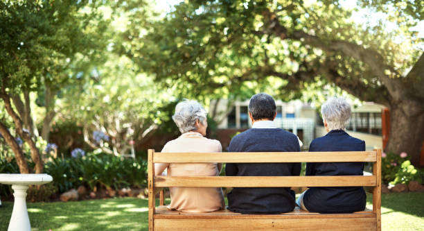 Peace and quite out in the gardens Rearview shot of a group of seniors sitting together on a bench out in the garden bench stock pictures, royalty-free photos & images