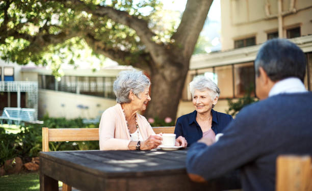 Good friends keep the happy times going Shot of a group of seniors having tea out in the garden of a retirement home retirement community stock pictures, royalty-free photos & images