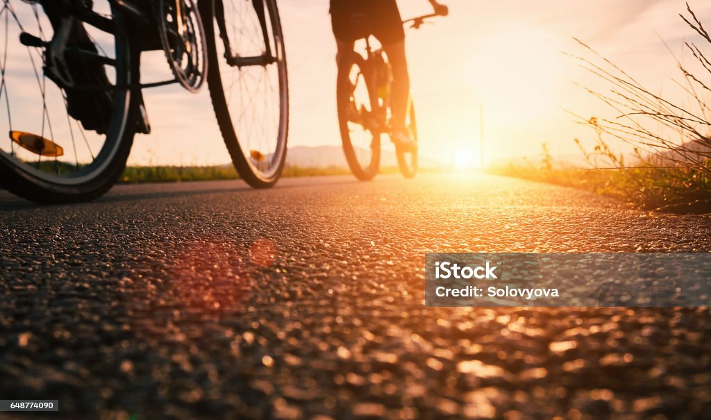 Fahrrad Räder schließen Sie herauf Bild auf Sonnenuntergang Asphaltstraße - Lizenzfrei Radfahren Stock-Foto