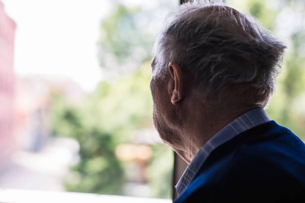 istock Lonely old man looking out of a window 648799694