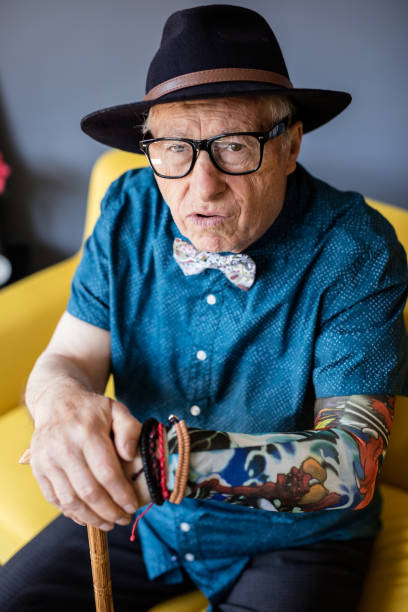 istock Grumpy senior man with cane and tattoo looking at camera 648803302