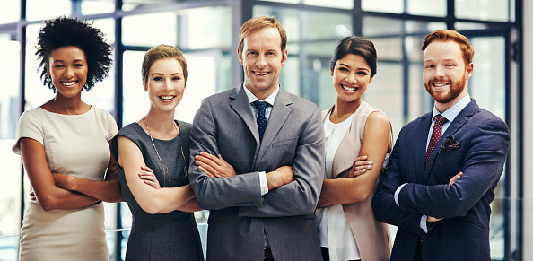 Portrait Of Multi-Cultural Office Staff Standing In Lobby Smiling At Camera