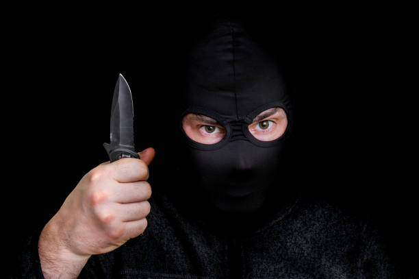 istock Masked man in balaclava with knife isolated on black 648811882