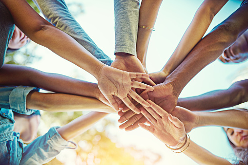 Top view closeup of senior people stacking hands in circle during support group session in retirement home