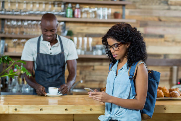 istock Woman using mobile phone while waiter standing in background 648822050