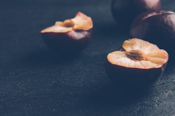 Fresh plums on a dark stone background