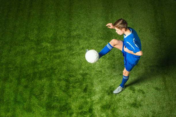 Young boy with soccer ball doing flying kick