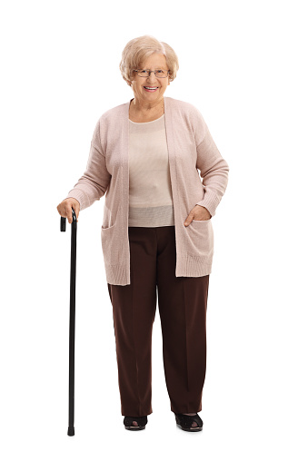 Full length portrait of an elderly woman with a walking cane smiling isolated on white background