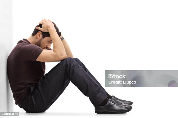 Depressed Man Sitting On The Floor With His Head Down Stock Photo - Download Image Now