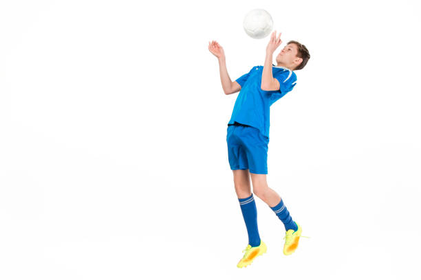 Young boy with soccer ball doing flying kick, isolated on white
