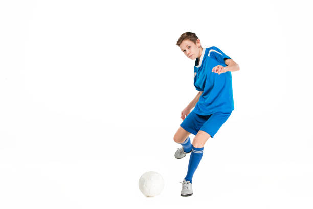 Young boy with soccer ball doing flying kick, isolated on white