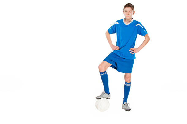 Young boy with soccer ball doing flying kick, isolated on white